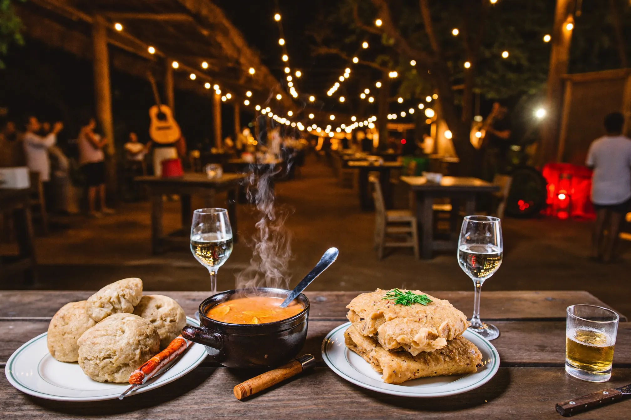 Illustrative image of a traditional Antioquian paisa fonda food village at night — wooden tables, sancocho and festival lights. AI-generated; not a photograph of any specific establishment.